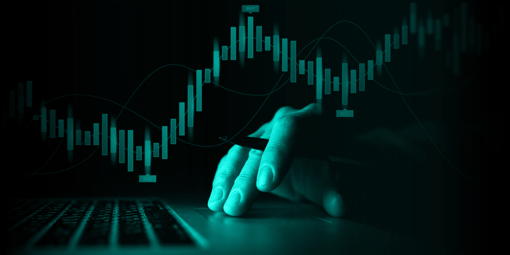 A hand and a laptop with candlesticks overlay in a dark background.